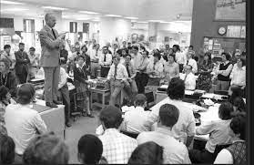 Clayton Kirkpatrick stands atop a desk in 1974 to share some true headline news