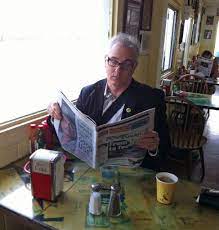 A Man Reading Newspaper Sitting Beside Window
